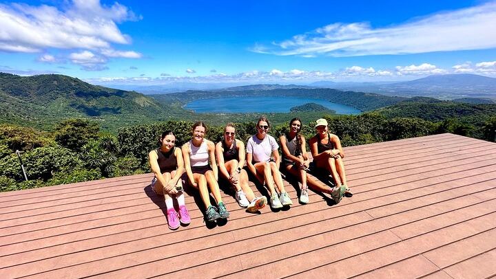 A group of female travelers are enjoying the Coatepeque Lake view from a restaurant after finishing the santa ana volcano hike