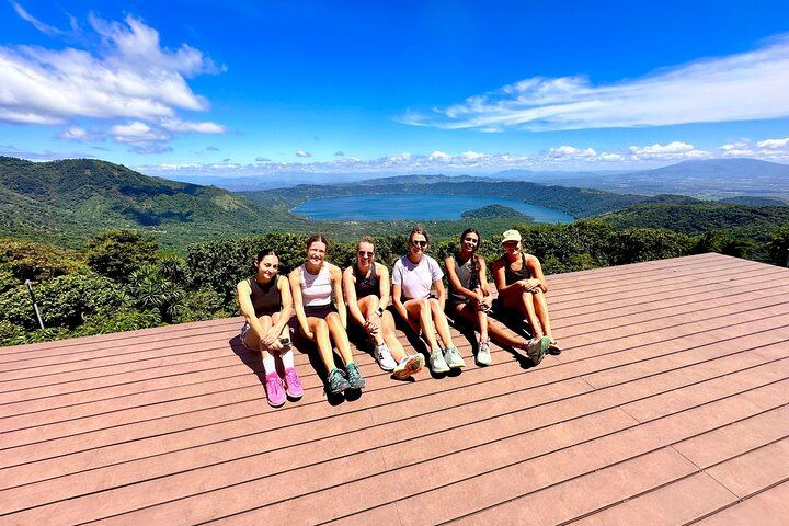 A group of female travelers are enjoying the Coatepeque Lake view from a restaurant after finishing the santa ana volcano hike