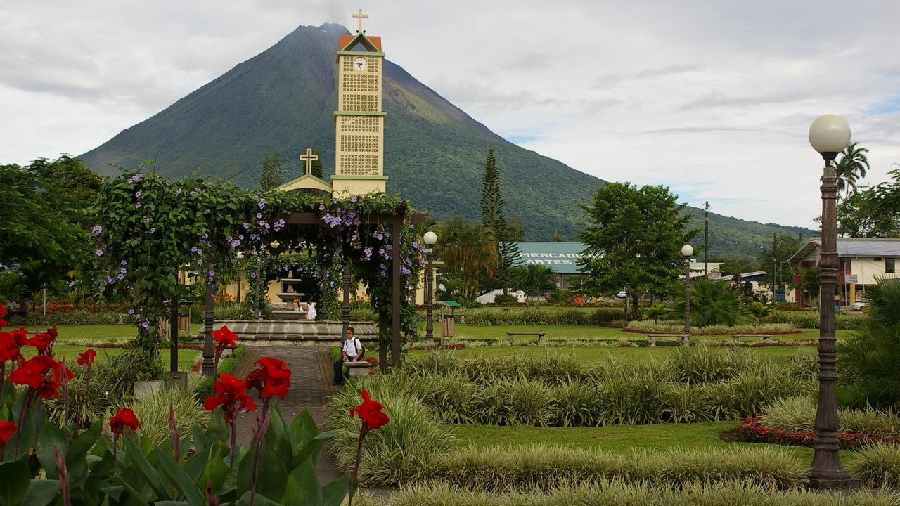 The Arenal volcano seen from the town of La Fortuna in Costa Rica, its cone rising above green farmland