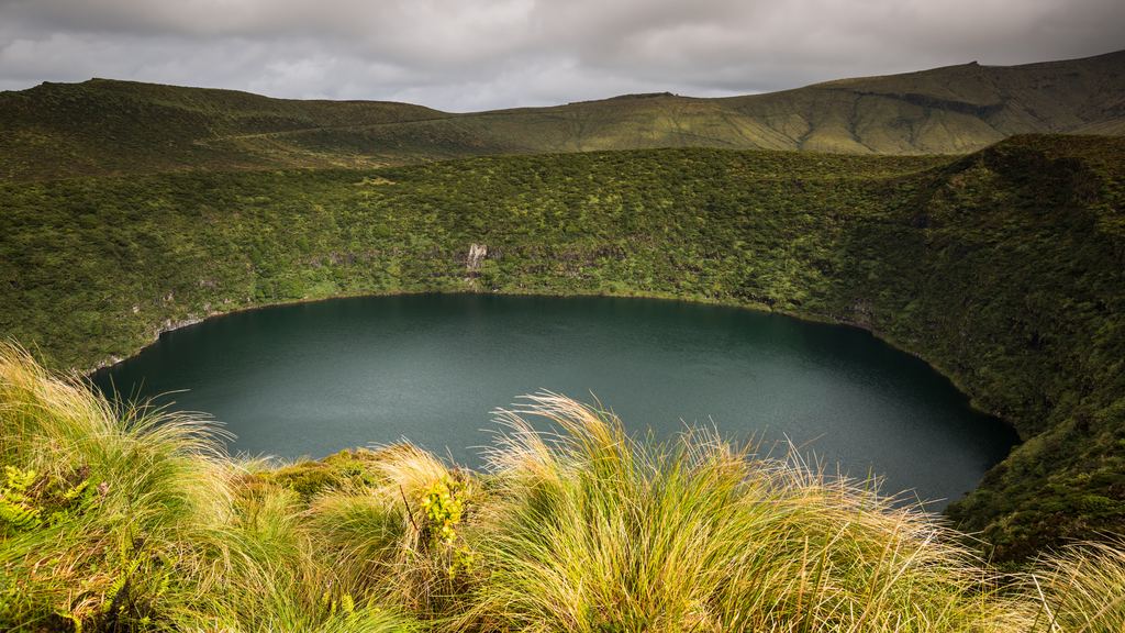 The Caldeira Funda crater lake surrounded by green slopes on Flores island, Azores