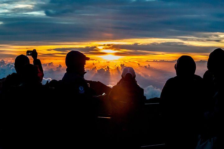 Day breaks over eager onlookers on Mount Haleakala at Haleakala National Park, Maui.
