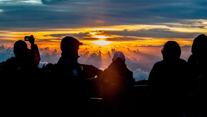 Day breaks over eager onlookers on Mount Haleakala at Haleakala National Park, Maui.