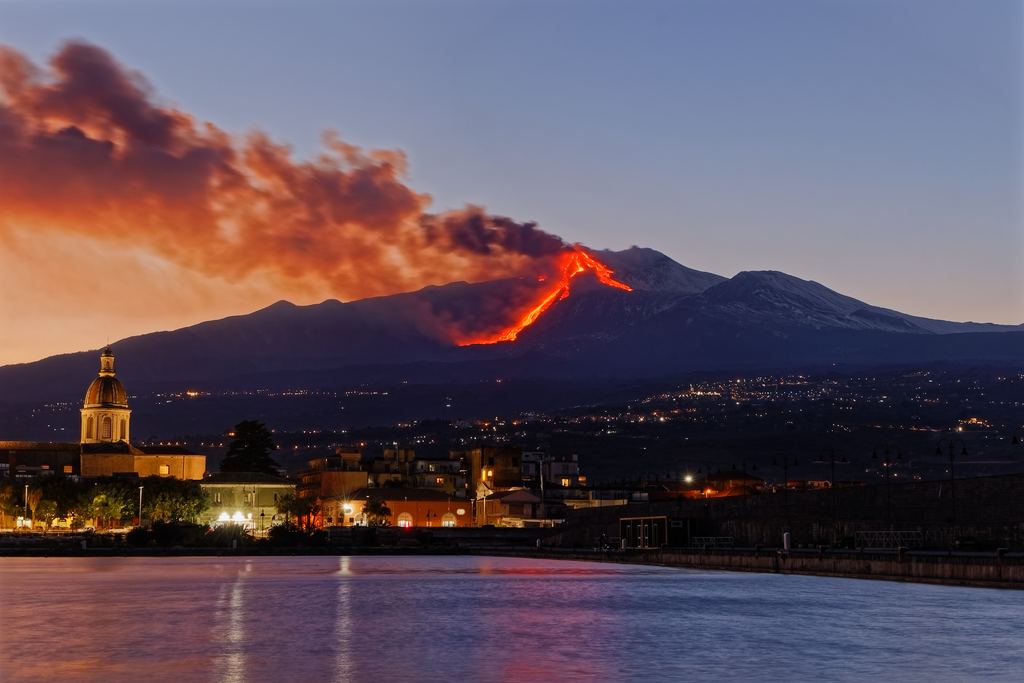Mount Etna in eruption seen at night from a town on its lower slopes, Sicily