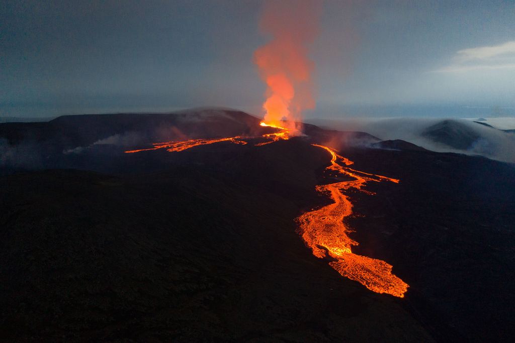 Aerial view of the Fagradalsfjall eruption in Iceland at dusk, with a lava field spreading across a valley