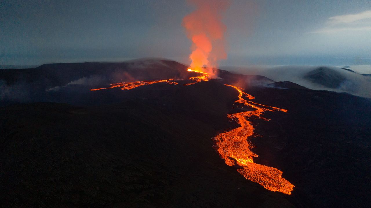 Aerial view of the Fagradalsfjall eruption in Iceland at dusk, with a lava field spreading across a valley