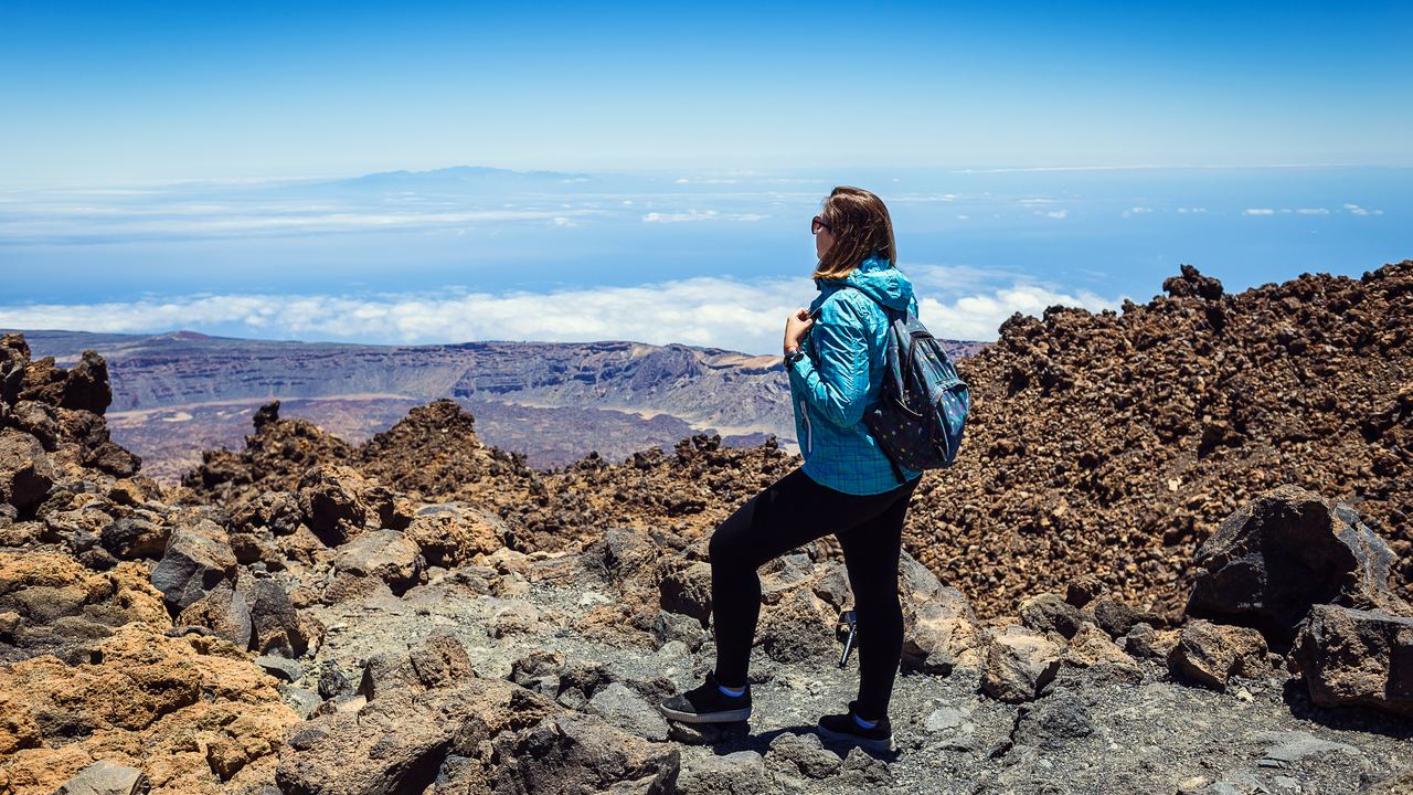 A hiker standing above a sea of clouds on the slopes of the Teide volcano in Tenerife, Canary Islands