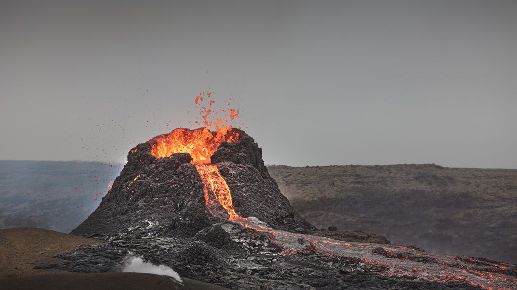 A tongue of glowing molten lava advancing over black cooled rock