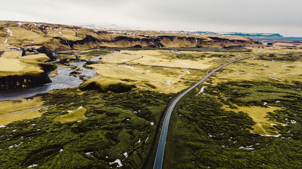 A road cutting through a green moss-covered lava field in Iceland