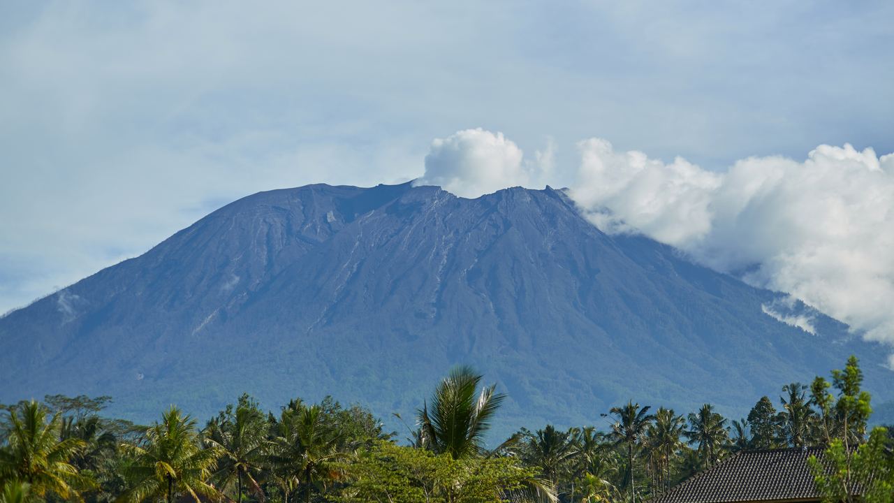 Mount Agung emitting steam in the morning, seen across green rice fields, Bali, Indonesia
