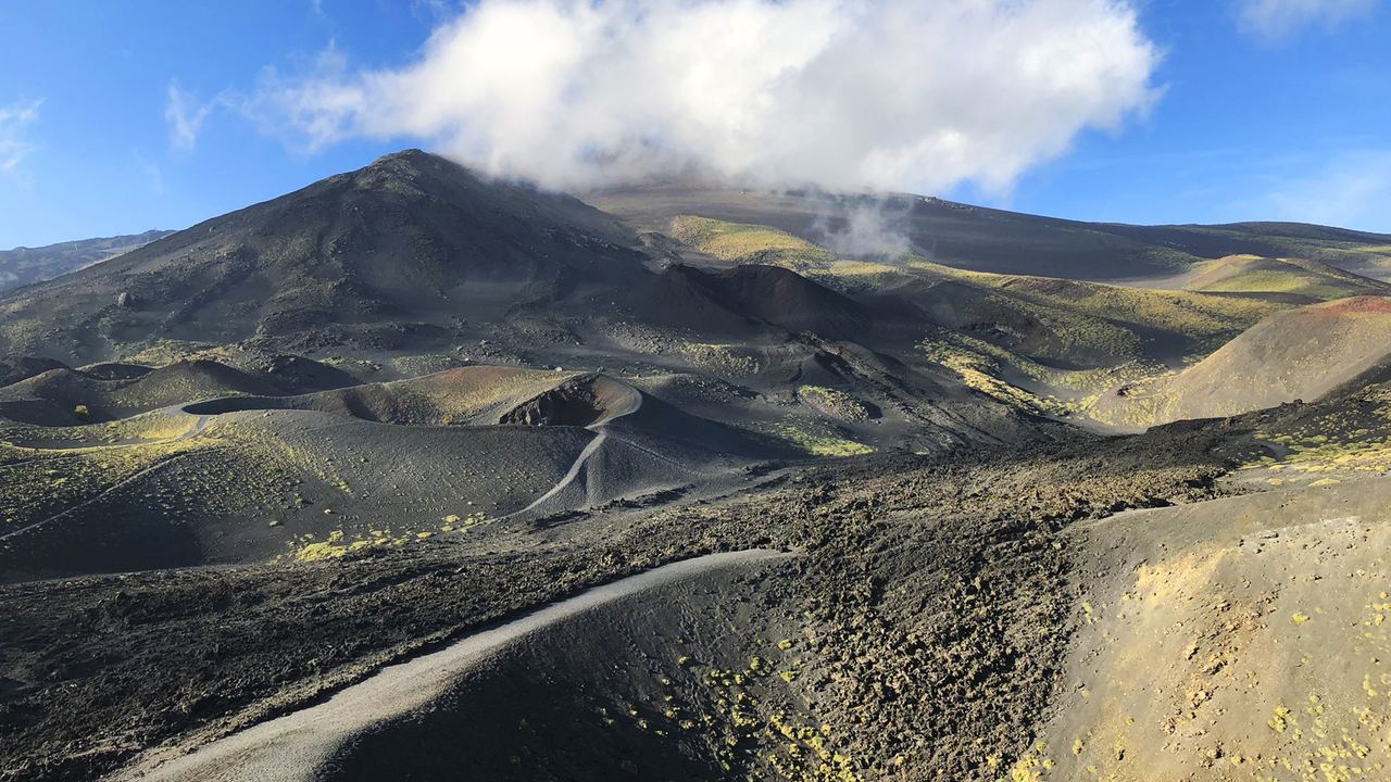 The summit crater field of Mount Etna in Sicily seen from the high slopes, with steam rising from several vents