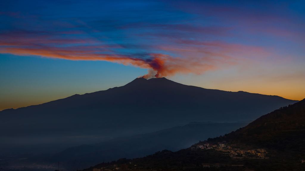 Snow covering the upper slopes of Mount Etna, with steam rising from the summit craters