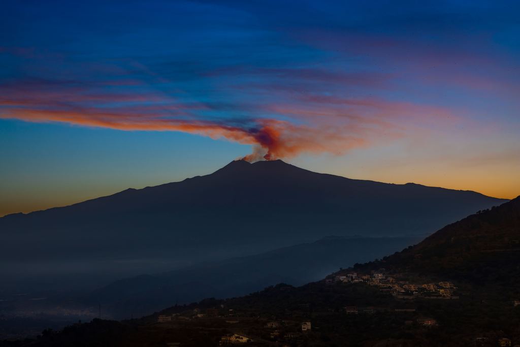 The snow-covered upper slopes of Mount Etna in Sicily with a steam plume above the summit craters