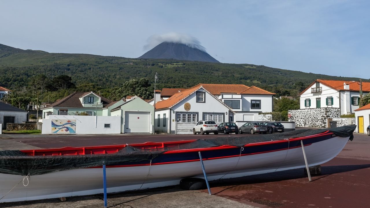 The cloud-capped peak of Mount Pico rising above houses and the harbour on Pico island, Azores