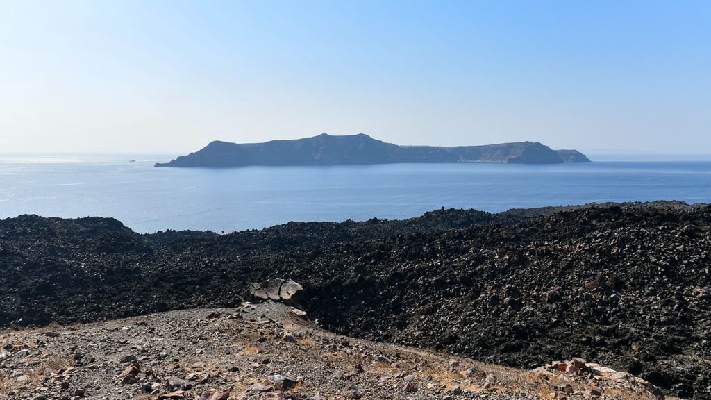 The low black lava island of Nea Kameni seen from a boat in the Santorini caldera