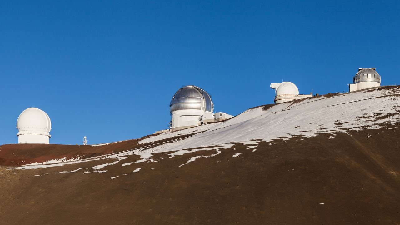 Observatory domes on the eastern side of the Mauna Kea summit standing above a layer of cloud