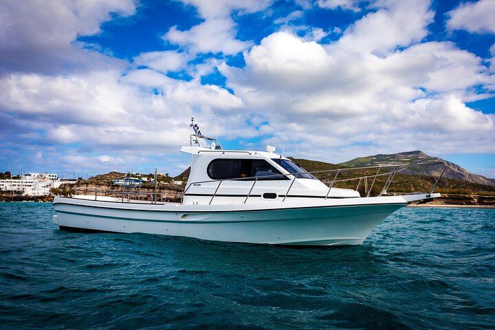 Our 10m 400HP Motor Boat cruising on blue water near a coastline under a partly cloudy sky.
