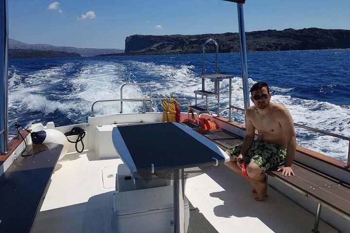 Plenty of space for one! Relaxe on the deck of a motor boat while cruising through the blue water of the Santorini caldera.