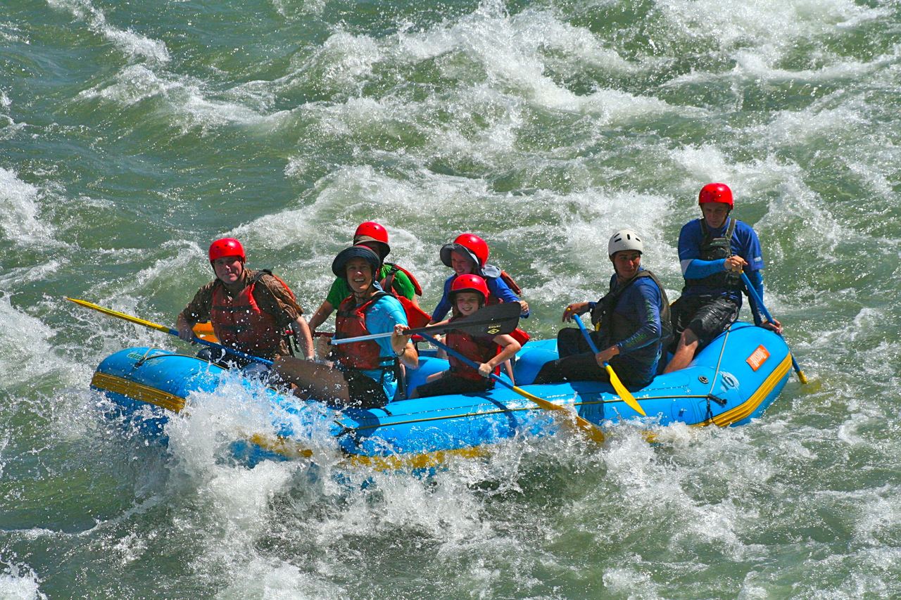 A raft crew paddling through whitewater on the Sarapiquí river in Costa Rica, in helmets and buoyancy aids
