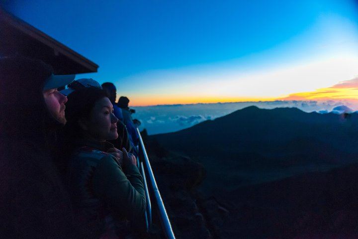 Rising sun highlights the face of an expectant onlooker on Mount Haleakala, Maui, Hawaii.