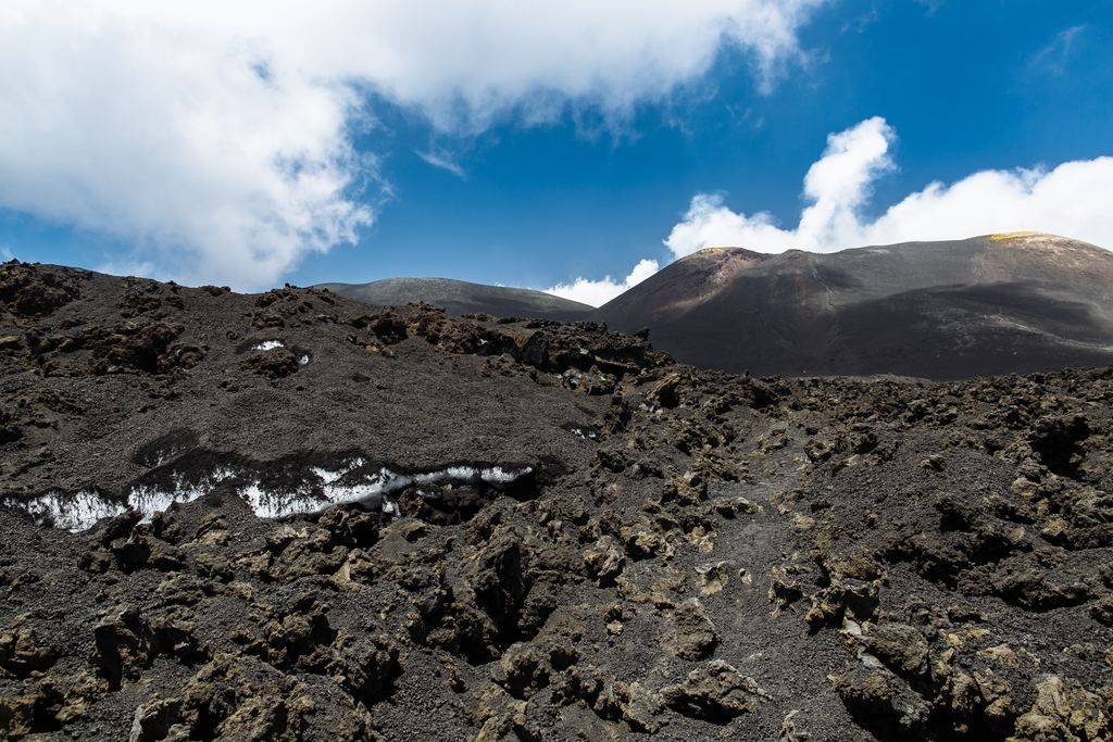 Layers of snow buried under black volcanic ash near the summit of Mount Etna in winter