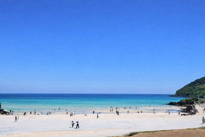 Soft white sand and clear emerald waters at Hamdeok Beach.
