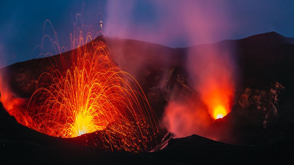 The volcanic island of Stromboli seen from the water, with a gas plume drifting from the summit