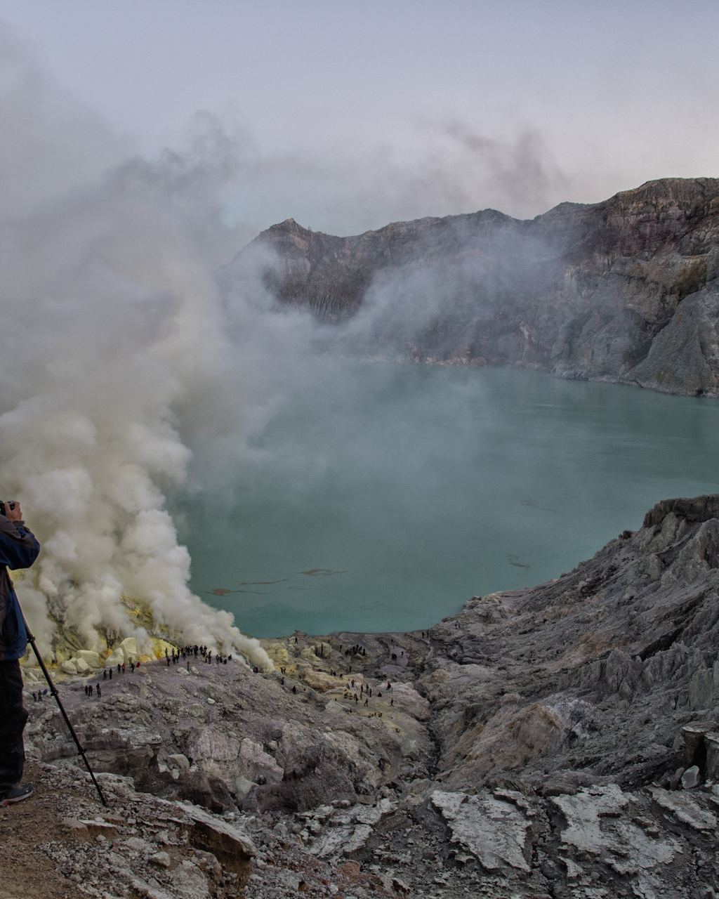 A sulphur miner carrying loaded baskets on a shoulder pole out of the Ijen crater at night, East Java