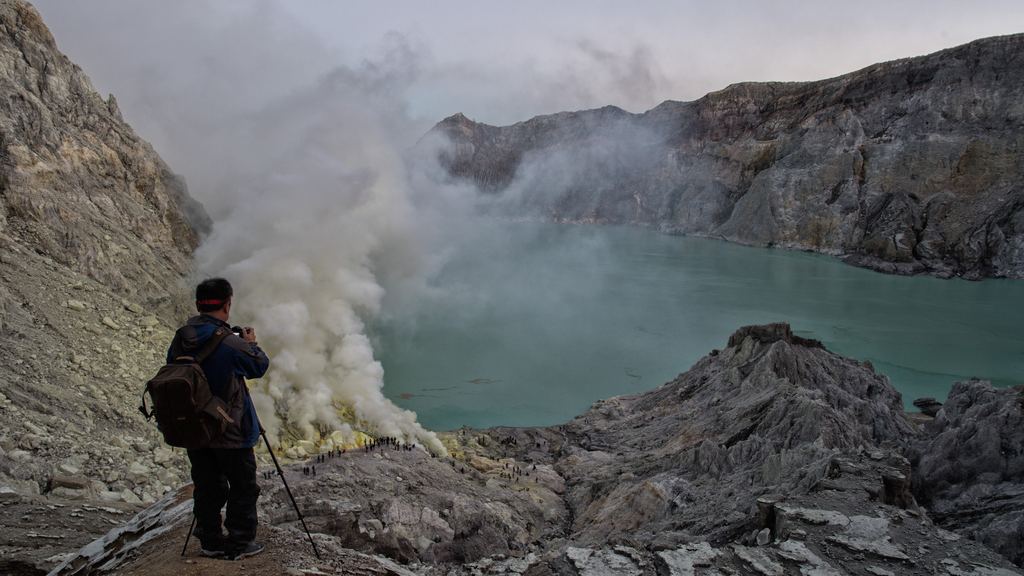 A sulphur miner carrying loaded baskets on a shoulder pole out of the Ijen crater at night