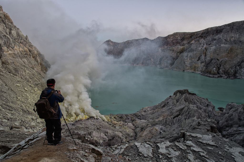 A sulphur miner carrying loaded baskets on a shoulder pole out of the Ijen crater at night, East Java