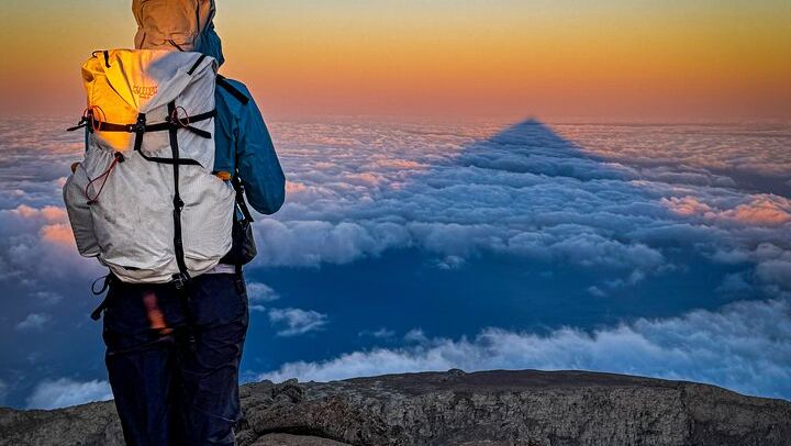 Sunrise and the mountain's shadow stretching across the clouds — pure magic after a night climb.