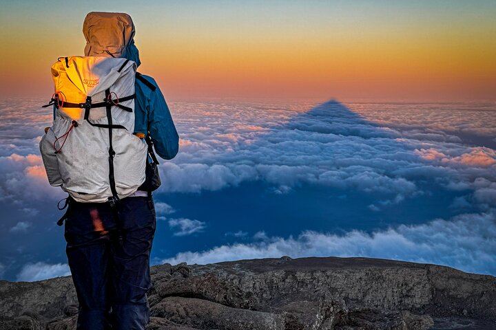 Sunrise and the mountain's shadow stretching across the clouds — pure magic after a night climb.