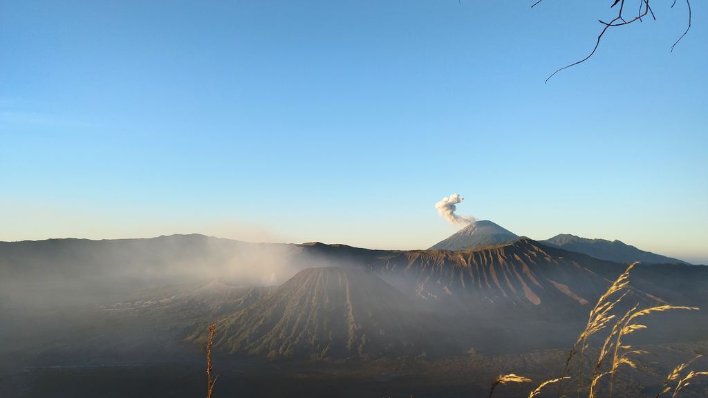 Mount Bromo and the Tengger caldera lit by early morning sun, with mist in the caldera floor
