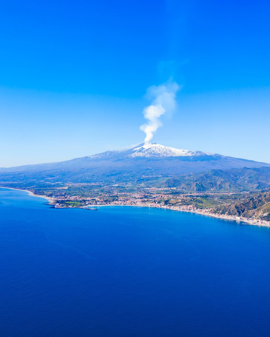 Aerial view of Taormina on the Ionian coast with Mount Etna rising behind the town