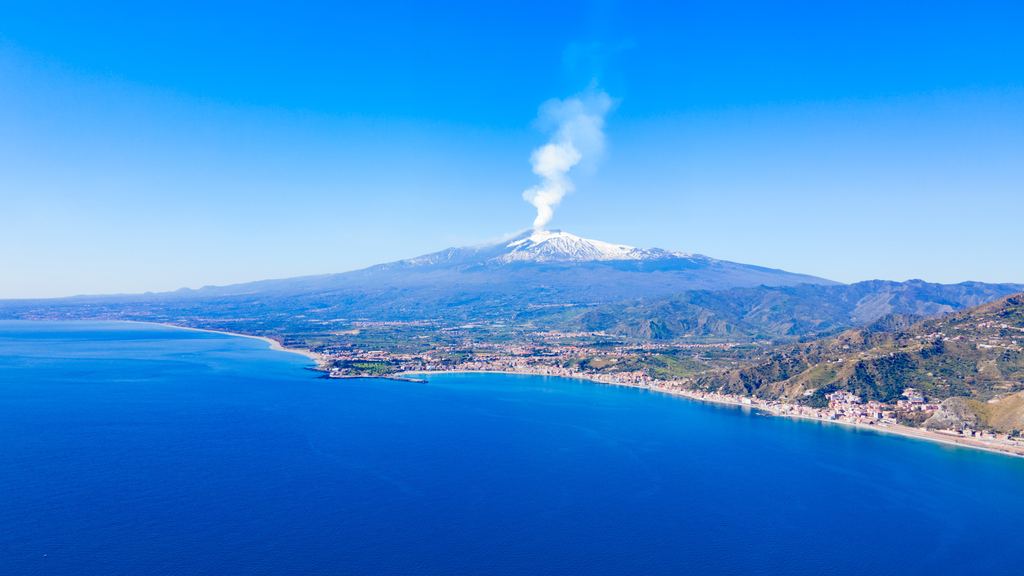 Aerial view of Taormina on the Ionian coast with Mount Etna rising behind the town