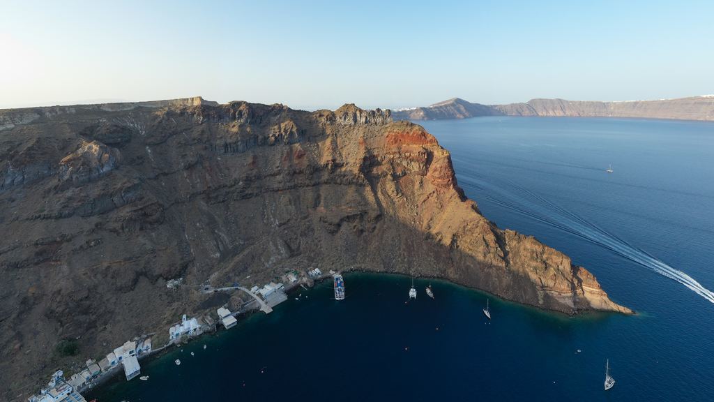 The layered volcanic cliffs of Thirassia seen across the water from Santorini