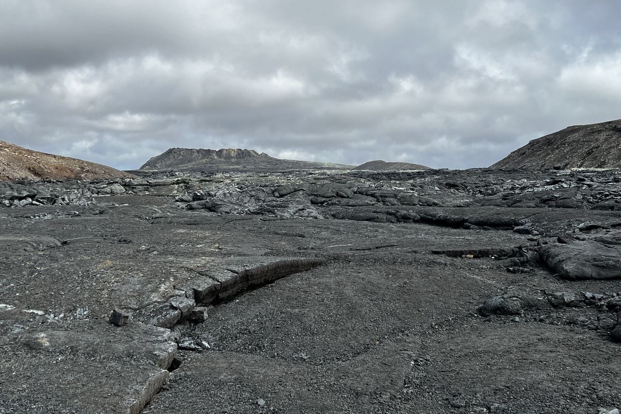 The cooled black lava field left by the 2021 Fagradalsfjall eruption in the Geldingadalir valley, with the crater on the skyline