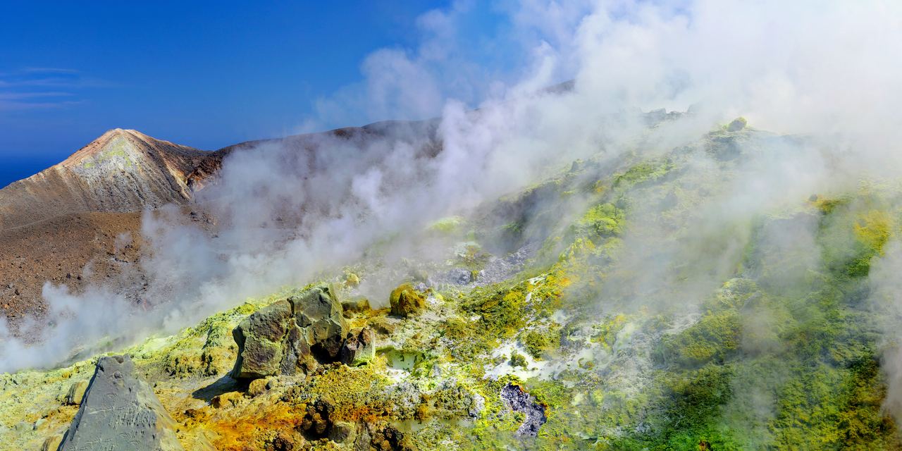 The rim of the Gran Cratere on Vulcano with fumaroles venting and a walker on the path