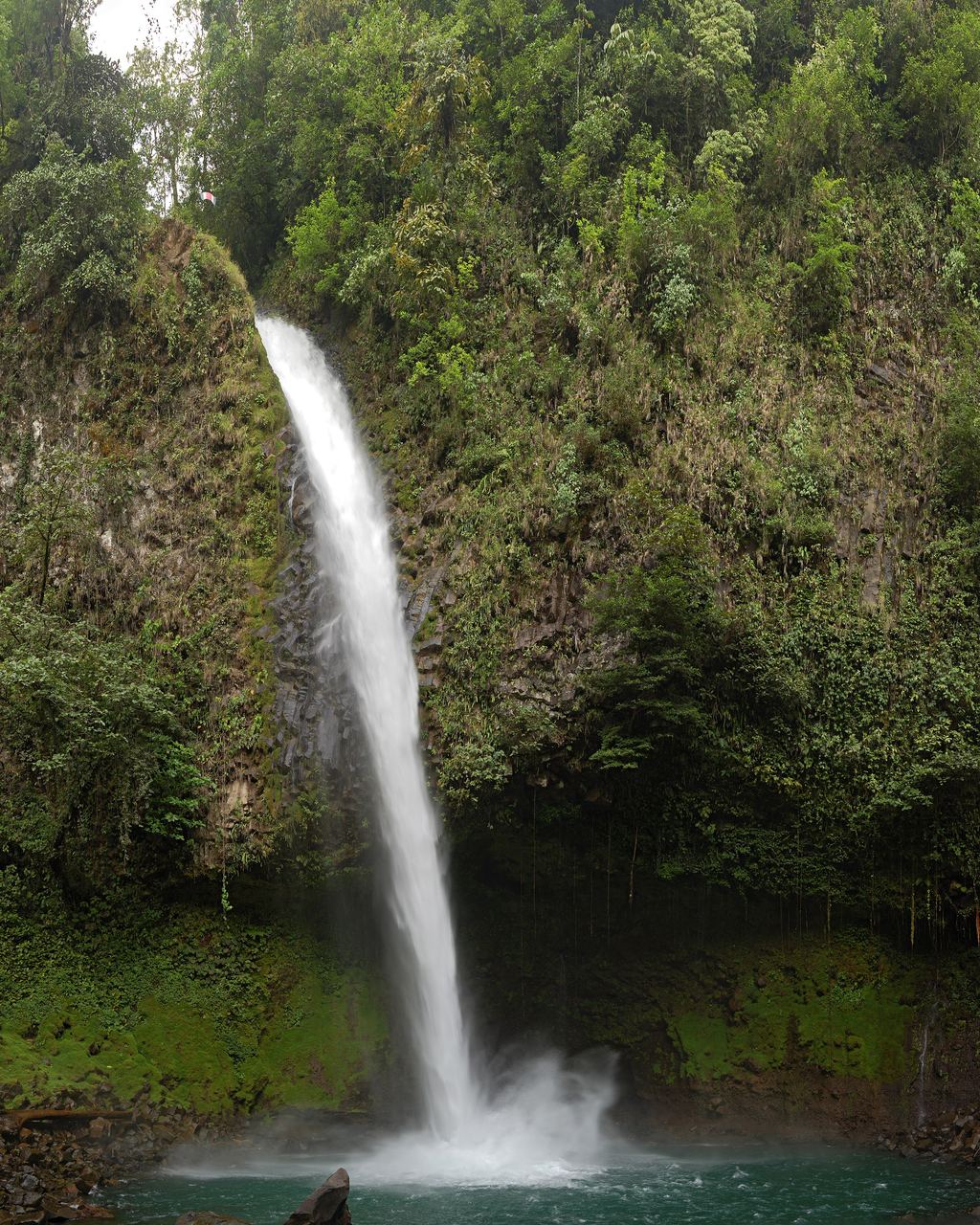 The plunge pool below the La Fortuna waterfall in Costa Rica, with boulders and the calmer water downstream