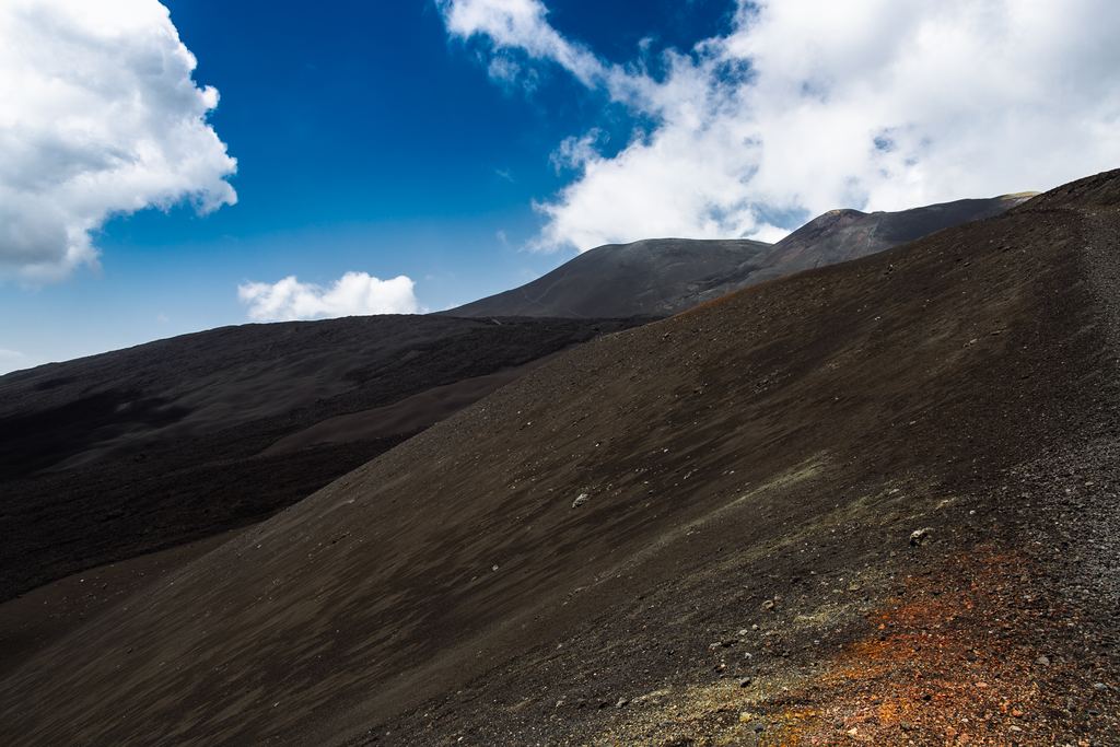 Close view of the loose black scoria and lava bombs covering the upper slopes of Mount Etna