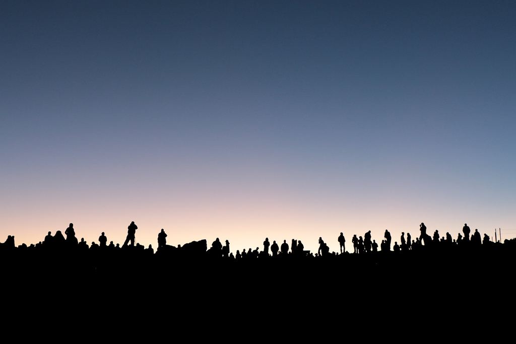 Visitors silhouetted against the sky waiting for sunrise on the summit of Haleakalā, Maui