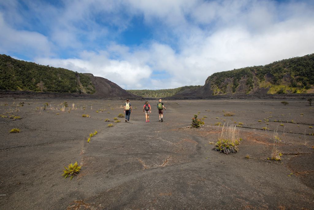 Hikers crossing the solidified lava lake on the floor of Kīlauea Iki crater, Hawaiʻi Volcanoes National Park